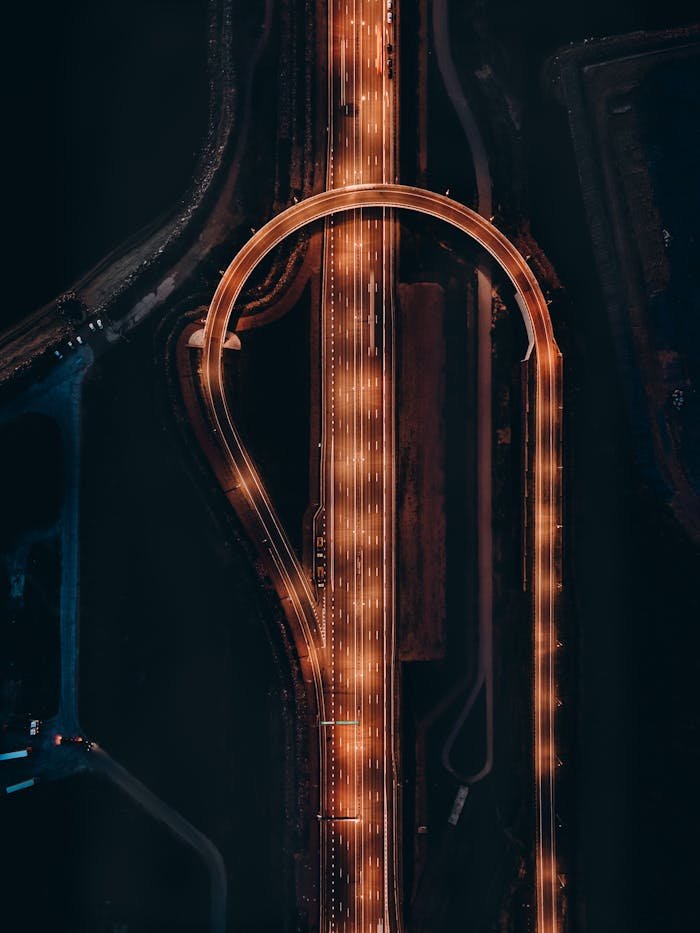 Stunning aerial photo of a glowing highway interchange during night, showcasing urban infrastructure.